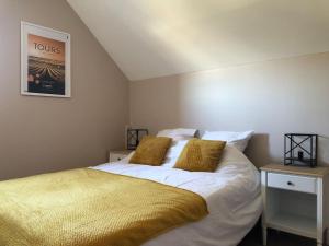 1 dormitorio con 1 cama con sábanas blancas y mantas amarillas en Maison tourangelle au coeur du vignoble Loire Valley, en Vouvray