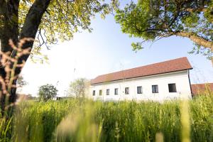 a white building with a red roof in a field at Die Arkade in Poppendorf im Burgenland