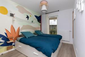 a bedroom with a bed with blue sheets and a mural at Iri Etxea - Appt 2 chambre à Bayonne in Bayonne