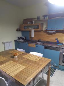 kuchnia z drewnianym stołem i niebieskimi szafkami w obiekcie Casa graziosa con ampio cortile per i tuoi momenti all'aperto w mieście Alghero +18 zdjęć