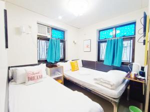 2 łóżka w pokoju z niebieskimi oknami w obiekcie Apple Hostel w Hongkongu