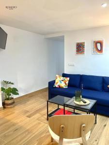 Romero Suites 1 في قرطبة: غرفة معيشة مع أريكة زرقاء وطاولة