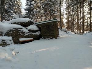 ein kleines Haus im Schnee mit einer Bank in der Unterkunft Hütte Waldesruh in Kaltenberg