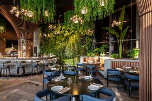 a restaurant with tables and chairs and plants at Ramada Olivie Nazareth in Nazareth