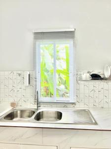 une cuisine blanche avec un évier et une fenêtre dans l'établissement Lay Back Villa C1with kitchen & High Speed Internet, à Krabi