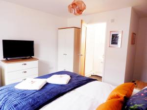 1 dormitorio con 1 cama y TV. en Modern, well located en-suite rooms with parking and all facilities en Cambridge