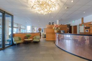 a lobby with a counter and chairs and a bar at Amrâth Hotel Alkmaar in Alkmaar