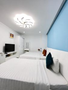 a white bedroom with two beds and a television at Valentine Luxury hotel - 31 Bui Vien Street in Ho Chi Minh City