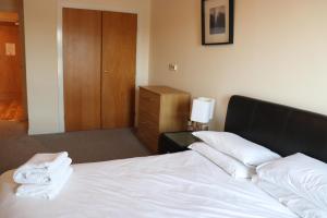 a bedroom with a white bed and a wooden cabinet at Century Wharf by Urban Space in Cardiff
