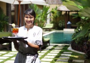 a woman holding a tray with a drink on it at O Villas Seminyak in Seminyak