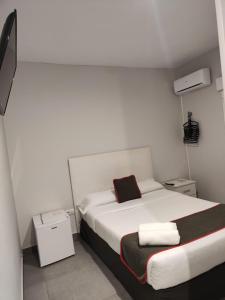 1 dormitorio con cama blanca y almohada roja en Hostal Jireh, en Alicante