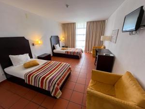 una habitación de hotel con 2 camas y una silla en Hotel Rural Santo Antonio en Arronches