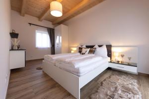 a white bedroom with a large white bed and a rug at Die Arkade in Poppendorf im Burgenland