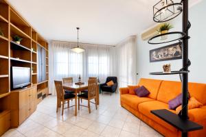 We Home - HOUSE OF STARS - Bologna في بولونيا: غرفة معيشة مع أريكة برتقالية وغرفة طعام