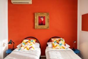 2 łóżka w pokoju z pomarańczową ścianą w obiekcie We Home - HOUSE OF STARS - Bologna w Bolonii