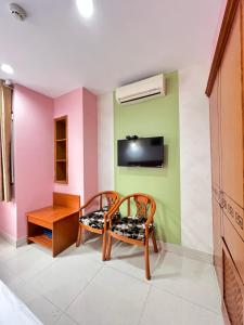 a room with two chairs and a tv on a wall at Valentine Luxury hotel - 31 Bui Vien Street in Ho Chi Minh City