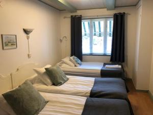 two beds in a room with a window at Hotell Turistgården i Simrishamn in Simrishamn