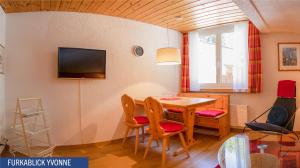 sala de estar con mesa, sillas y TV en Furkablick Alice und Yvonne by Arosa Holiday, en Arosa