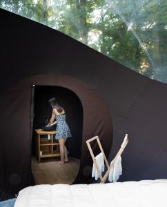 a woman standing at a table in a black tent at Chrysalide Saint Martin in Nérac