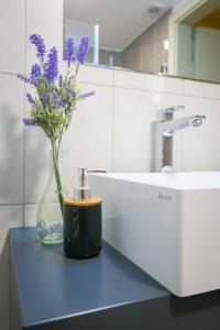 a vase of purple flowers sitting on a counter next to a sink at Barkóscinege Vendégház in Géberjén