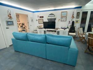 ein blaues Sofa im Wohnzimmer mit einem TV in der Unterkunft Ático con vistas al mar in Balerma