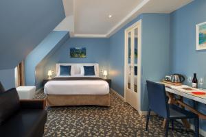 Habitación azul con cama y escritorio. en Grand Hôtel Malher, en París