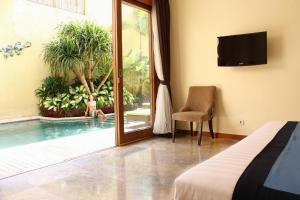 a bedroom with a view of a pool and a bed and a tv at O Villas Seminyak in Seminyak