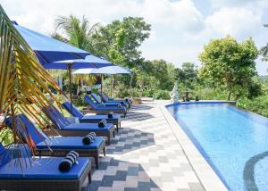 een zwembad met blauwe ligstoelen en parasols bij Penida Sunset Ocean View Bungalows in Nusa Penida