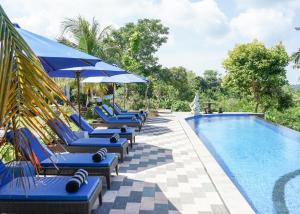 a pool with blue lounge chairs and umbrellas at Penida Sunset Ocean View Bungalows in Nusa Penida