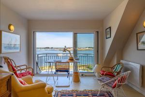 ロクテュディにあるMaison de 4 chambres a Loctudy a 100 m de la plage avec vue sur la mer jardin clos et wifiのリビングルーム(テーブル、椅子付)、バルコニーが備わります。