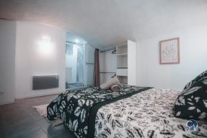 een slaapkamer met een bed met een zwart-witte deken bij Appartement neuf et moderne dans le centre ville in Bagnols-sur-Cèze
