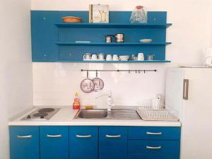 eine Küche mit blauen Schränken und einem weißen Kühlschrank in der Unterkunft Apartmani Diego in Sveta Nedelja
