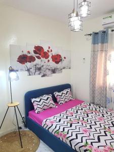 1 dormitorio con 1 cama con flores rojas en la pared en Charmant F3, 2 chambres + salon à Yoff plage bceao, en Dakar