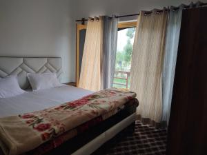 a bedroom with a bed and a large window at Skayil House in Nubra