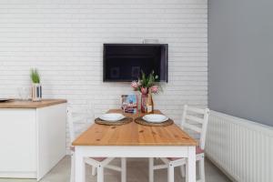 a wooden table with two plates and a tv on a wall at Dobrego Pasterza Studio with Balcony Cracow by Renters in Kraków