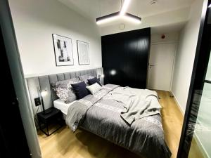 a bedroom with a bed and a black wall at O! Shellter Apartment PREMIUM by Oskar in Rogowo