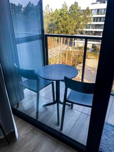 une table et deux chaises assises à côté d'une fenêtre dans l'établissement O! Shellter Apartment PREMIUM by Oskar, à Rogowo