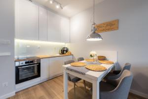 a kitchen with a white table and chairs in a room at Horyzont Apartamenty -Bałtycka2 - SAUNA & FITNESS - ŚNIADANIA in Kołobrzeg