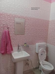 a pink bathroom with a toilet and a sink at Hotel Supreme & Banquet in Sirhind