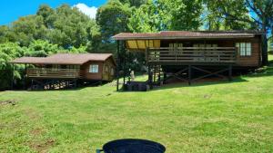 uma cabana de madeira e um edifício num campo de relva em Lisbon Eco Lodge em Graskop