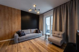a living room with a couch and a chair at Horyzont Apartamenty -Bałtycka2 - SAUNA & FITNESS - ŚNIADANIA in Kołobrzeg