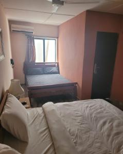 um quarto com uma cama e um piano ao lado de uma janela em Eko Akete Guest House em Abeokuta