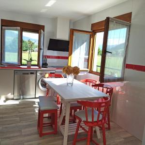 cocina con mesa blanca y sillas rojas en Apartamentos La casa del Zapatero, en Corvera