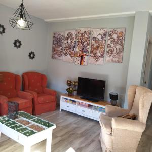 a living room with two chairs and a television at Apartamentos La casa del Zapatero in Corvera