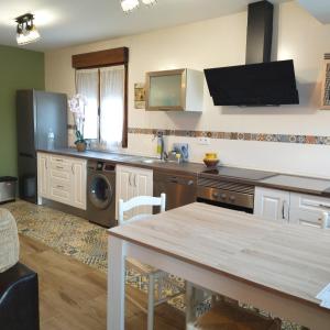 a kitchen with a table and a dishwasher at Apartamentos La casa del Zapatero in Corvera