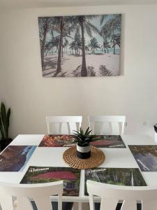 a white dining room table with a potted plant on it at Cocooning en rez de jardin in Saint-Pierre