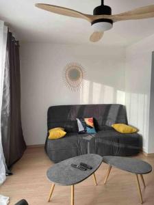 a living room with a black couch and two tables at Cocooning en rez de jardin in Saint-Pierre