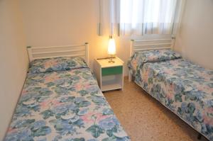 a bedroom with two beds and a table with a lamp at Appartamenti Villa Frediana in Bibione