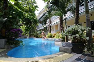 una mujer sentada en una piscina en un resort en Naka Resort en Kamala Beach