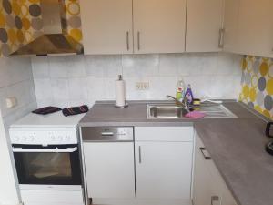 a kitchen with white cabinets and a sink and a stove at Ferienwohnung Ernst 10 in Gelenau